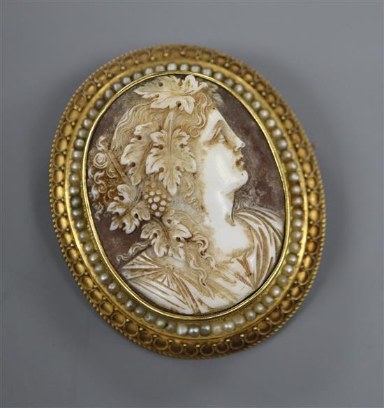 A yellow metal (tests as 18ct) and seed pearl mounted oval cameo brooch, carved with the bust of a lady to sinister, 51mm.